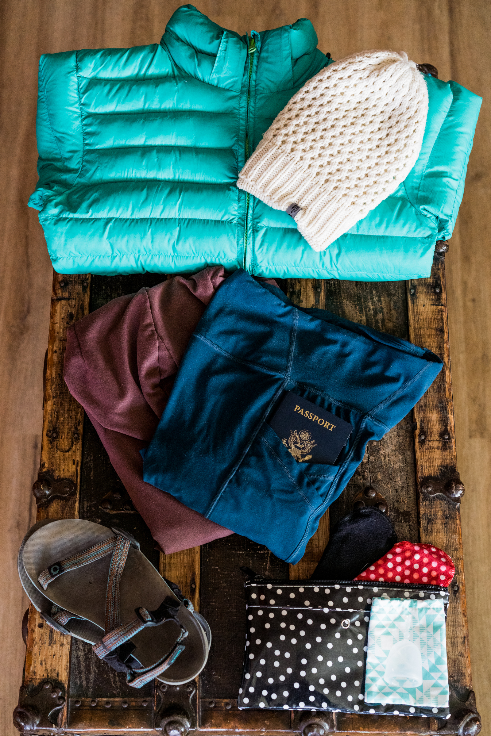 A puffy jacket, beanie, yoga pants, passport, and reusable period products. 