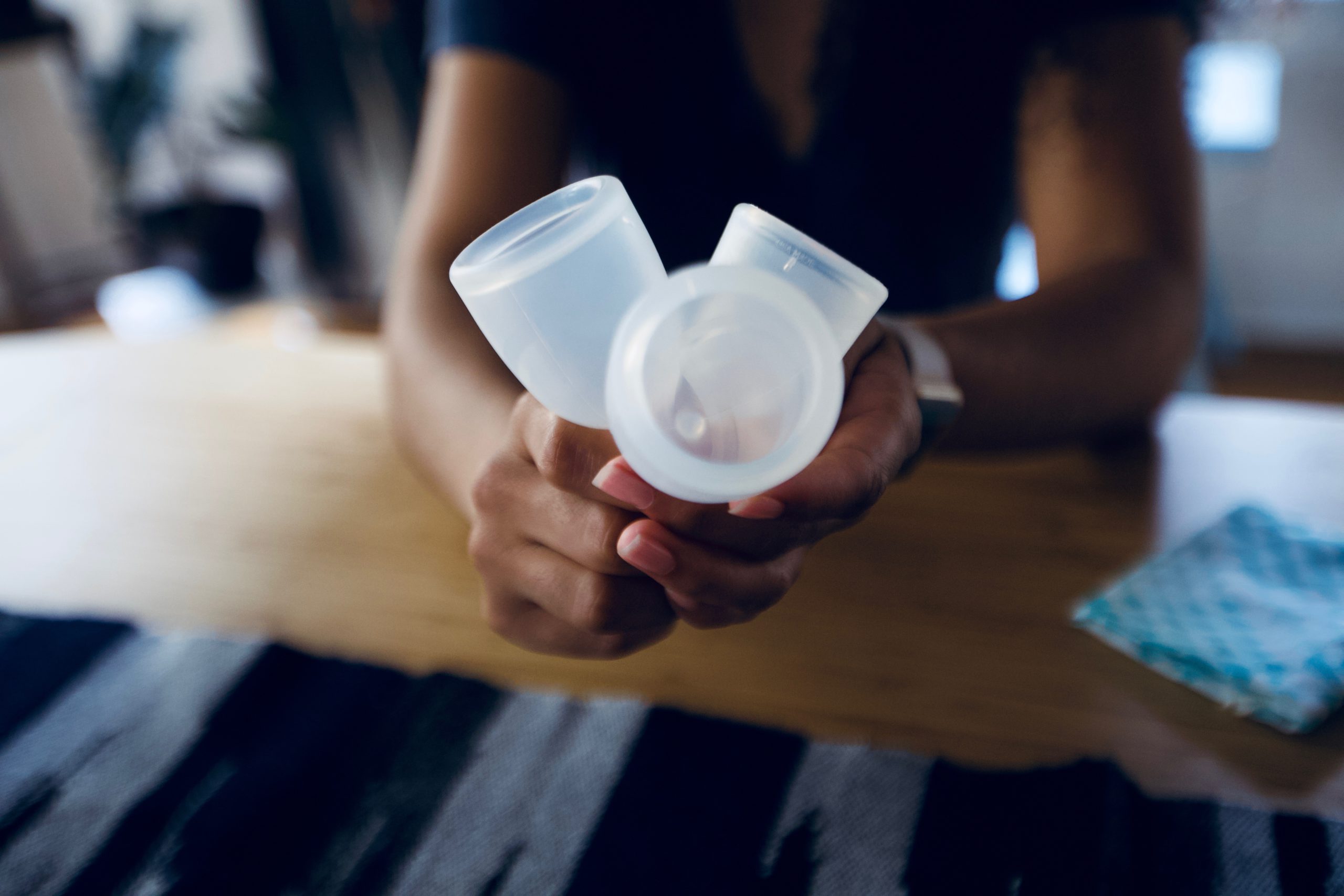 A person holds three menstrual cups like a bouquet.