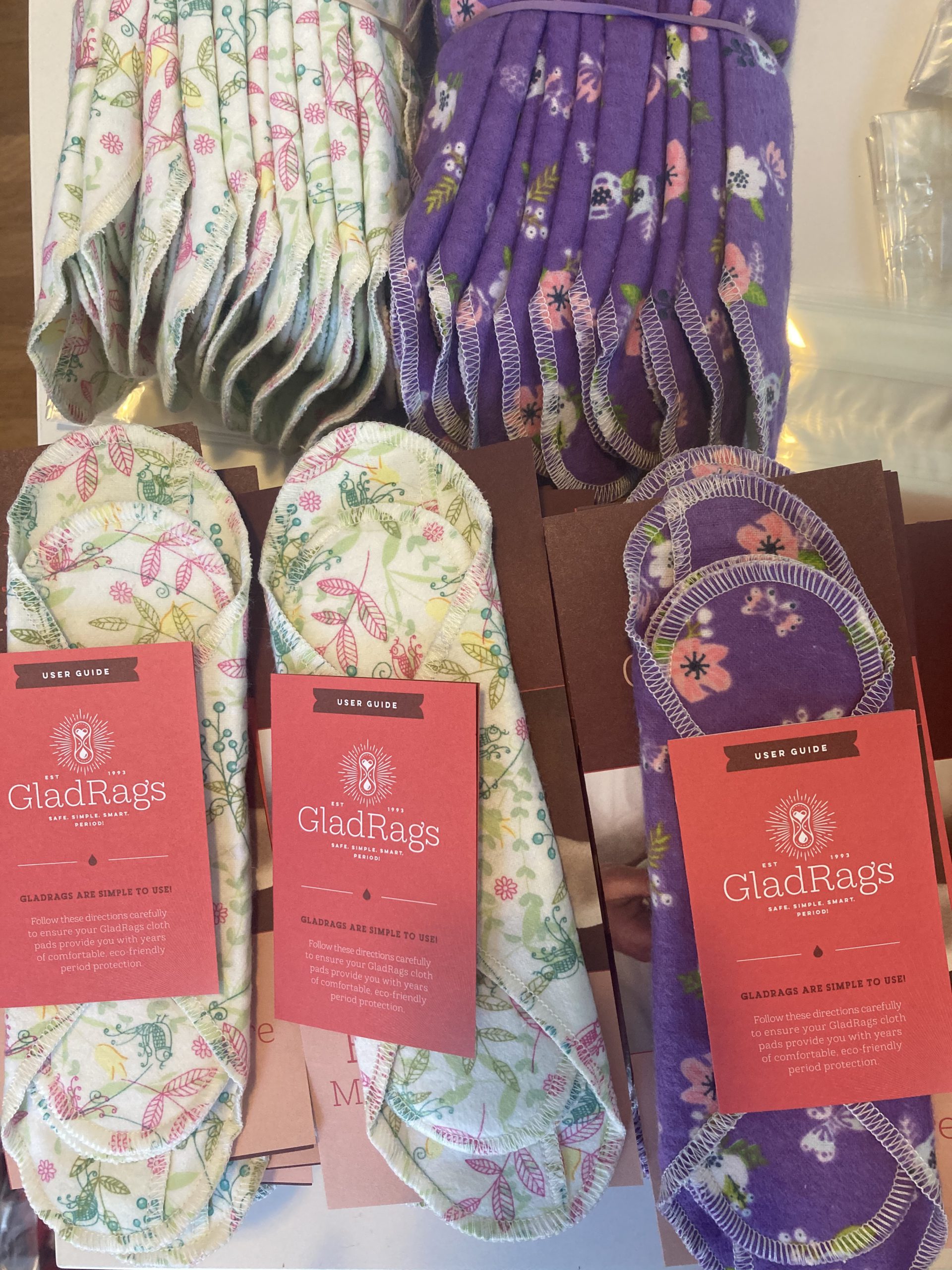 cloth pads in floral prints sit on top of boxes ready to ship out, a GladRags printed user guide is on each one.